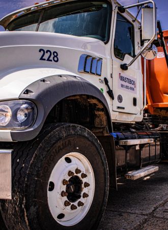 A large semi-truck hauling an orange dumpster.