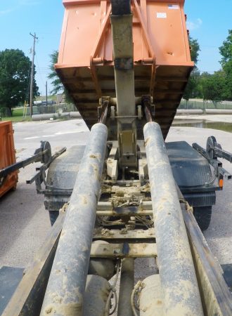 An orange roll off dumpster being delivered to a client.